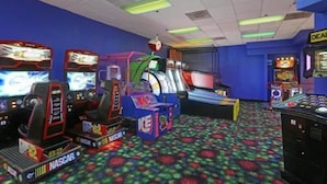 A room with multiple arcade machines, including a racing game and a claw machine. - Seralago Hotel and Suites Main Gate East (Kissimmee)