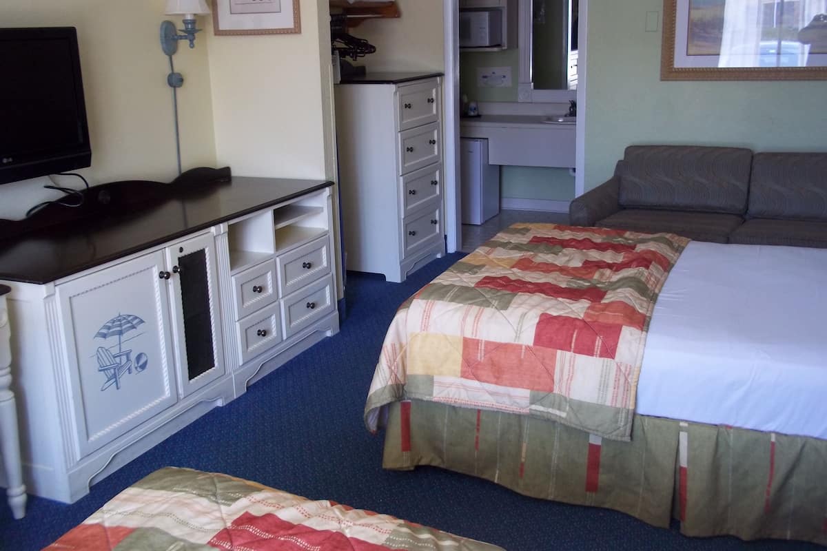 Une chambre à coucher avec un lit, une commode, un téléviseur et un bureau.