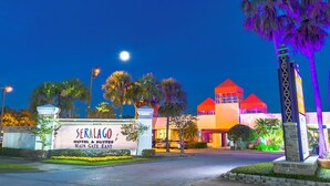 A hotel entrance with a sign reading "SERALGO HOTEL & SUITES MAIN GATE EAST" and a well-lit building with a red roof and multiple stories. - Seralago Hotel and Suites Main Gate East (Kissimmee)