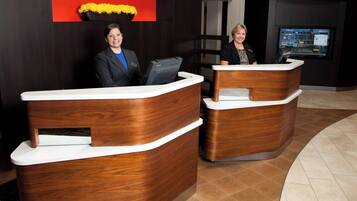 A reception desk with a modern design, a digital screen displaying information, and a nameplate above the desk.