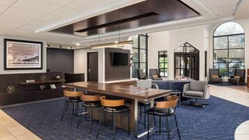 A modern hotel lobby with a large bar area, comfortable seating, and large windows offering views of the outdoors.