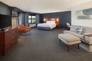 Una habitación de hotel con cama, escritorio, silla, sofá y televisor.
