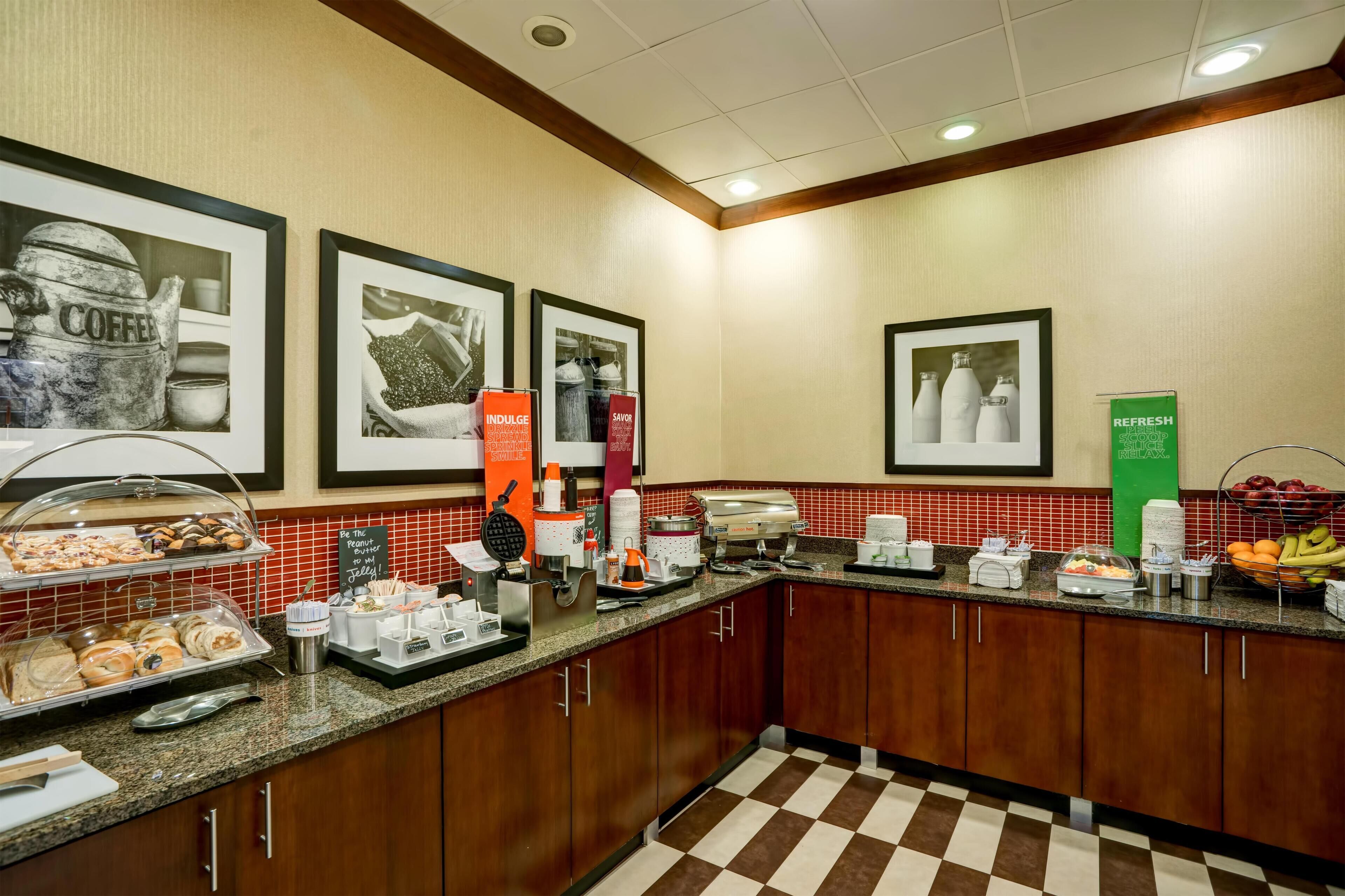 A hotel kitchen with a buffet area, coffee machines, and a fruit bowl.