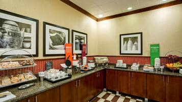 A hotel kitchen with a buffet area, coffee machines, and a fruit bowl.