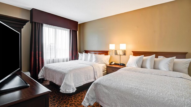 A hotel room with two beds, a TV, and a desk.