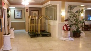 A hallway with a golden elevator, a snowman decoration, and potted plants. - Imperial Swan Hotel & Suites (Lakeland)