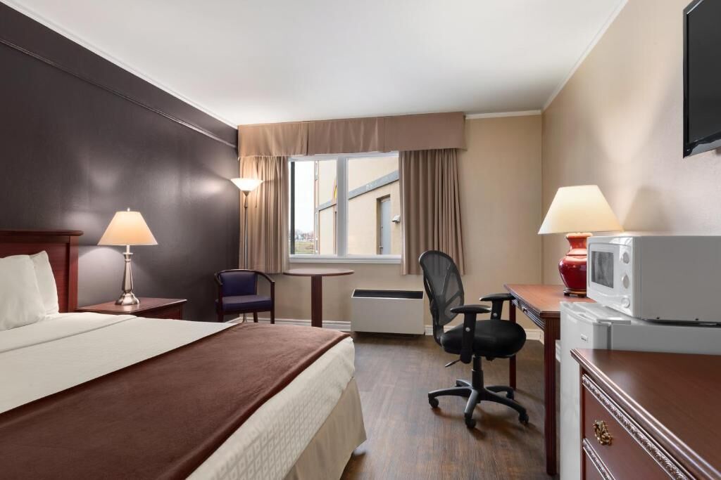 Una habitación de hotel con cama, escritorio, silla y televisor.