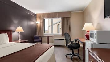 Una habitación de hotel con cama, escritorio, silla y televisor.