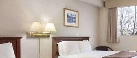 A hotel room with two beds, a nightstand, a lamp, a framed picture on the wall, and a window with curtains.