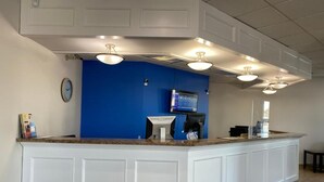 A reception area with a blue accent wall, a clock, a television, and a reception desk. - SureStay by Best Western Brockville (Brockville)