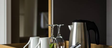 A wooden tray with a kettle, two cups, and a glass.