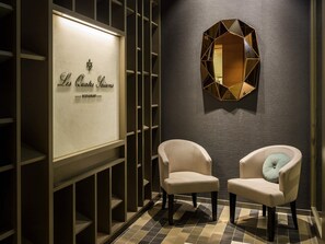 A modern interior with a wall-mounted sign reading 'Les Quatre Saisons RESTAURANT' and two upholstered chairs with cushions. - Pullman Basel Europe (Basel)