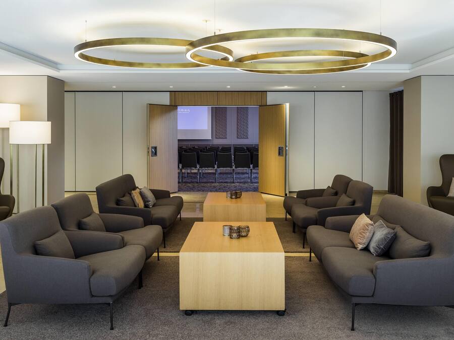 Un vestíbulo moderno con una mesa de centro, sofás y una sala de conferencias con sillas.