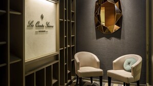 A modern interior with a wall-mounted sign reading "Les Quatre Saisons RESTAURANT" and two upholstered chairs with cushions. - Pullman Basel Europe (Basel)