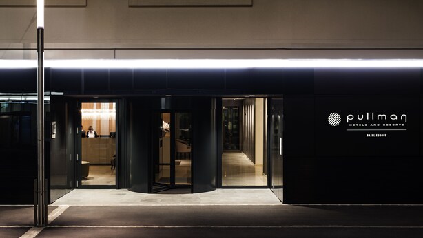 L’entrée d’un hôtel au design moderne, avec une porte en verre et une enseigne indiquant « Pullman Hotels and Resorts », à Bâle, en Europe.