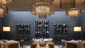 A dining area with round tables, gold serving dishes, and geometric wall art. - Pullman Basel Europe (Basel)