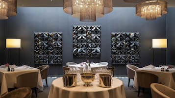 Un comedor con mesas redondas, vajilla dorada y arte geométrico en las paredes.