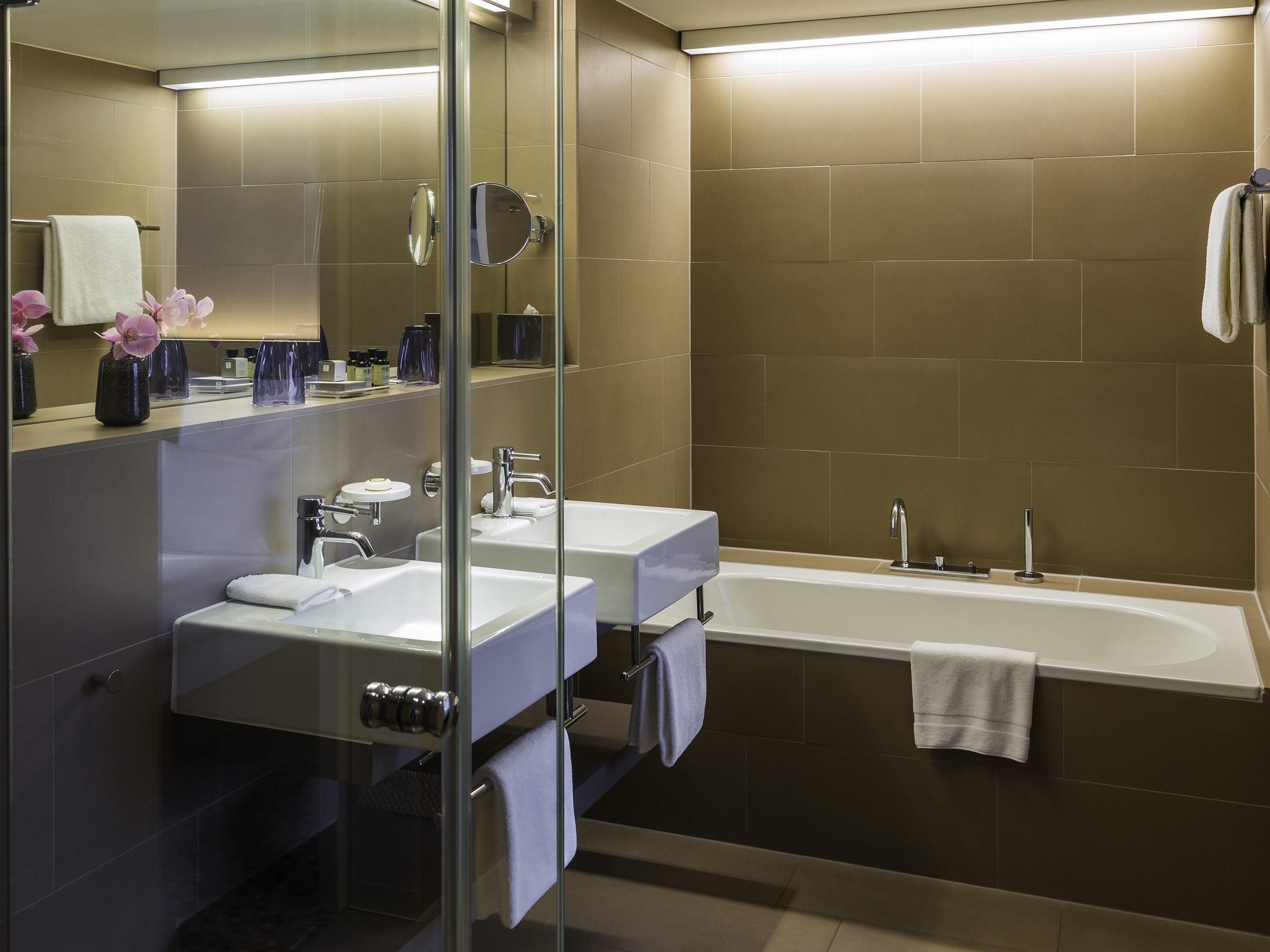 Een moderne badkamer met twee wastafels, een bad en een douchecabine met glazen wanden.