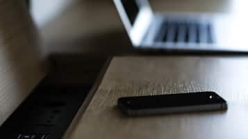 A wooden table with a smartphone and a laptop.