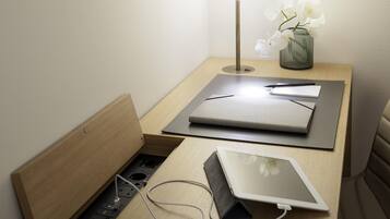 Ein ordentlicher Arbeitsplatz mit einem Laptop, einem Tablet, einer Lampe und einer Vase mit Blumen auf einem Nachttisch aus Holz.