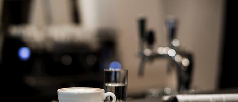 A cup of coffee and a glass of water on a tray.
