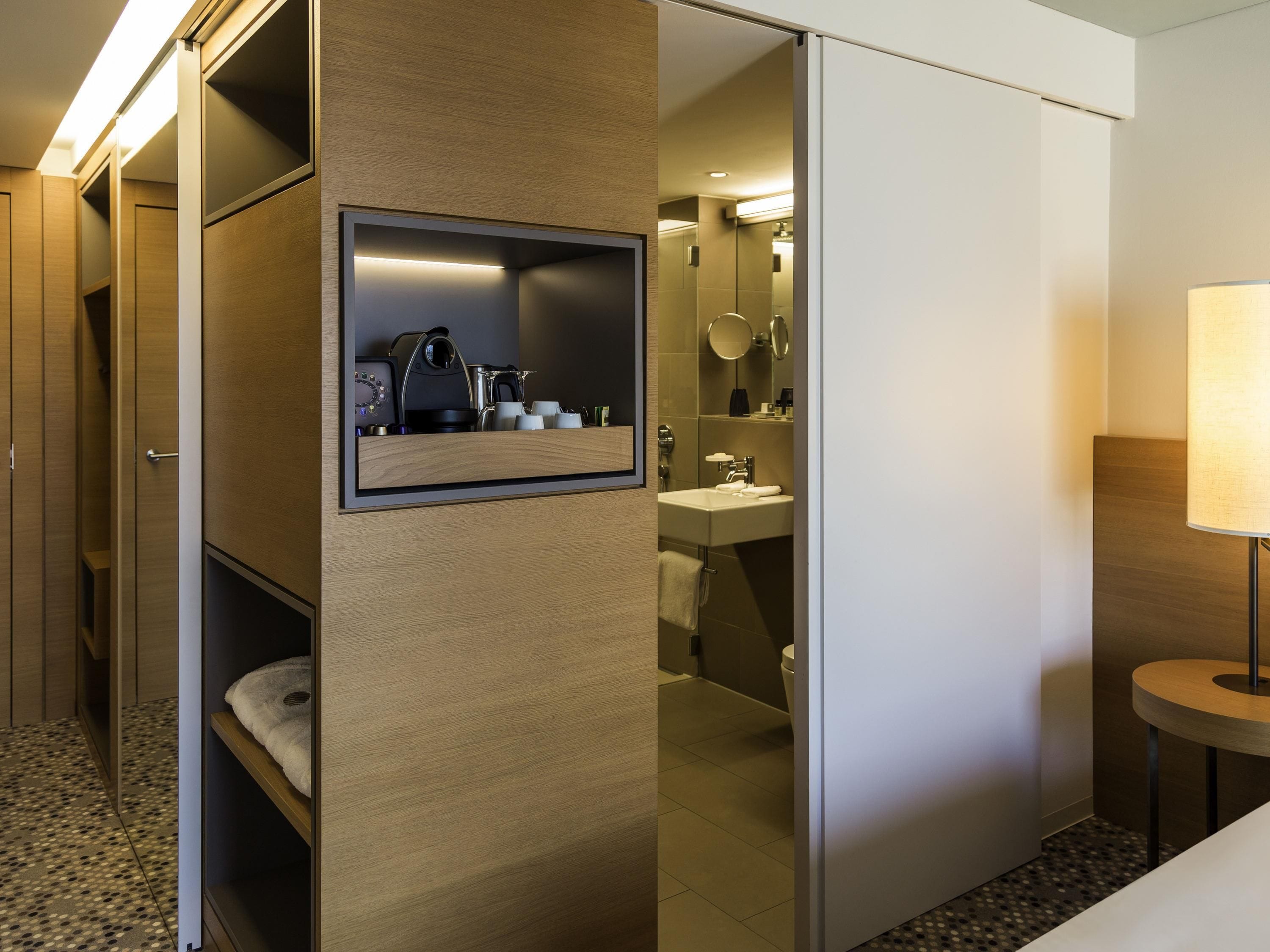 Una habitación de hotel con escritorio integrado, espejo, lavamanos y retrete.