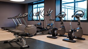 Une salle de sport dotée de nombreux appareils de cardio, de grandes fenêtres et d’un design moderne.