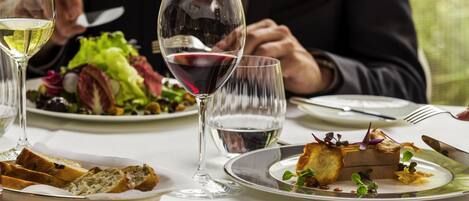 Una mesa de comedor con platos de comida, copas de vino y cubiertos.
