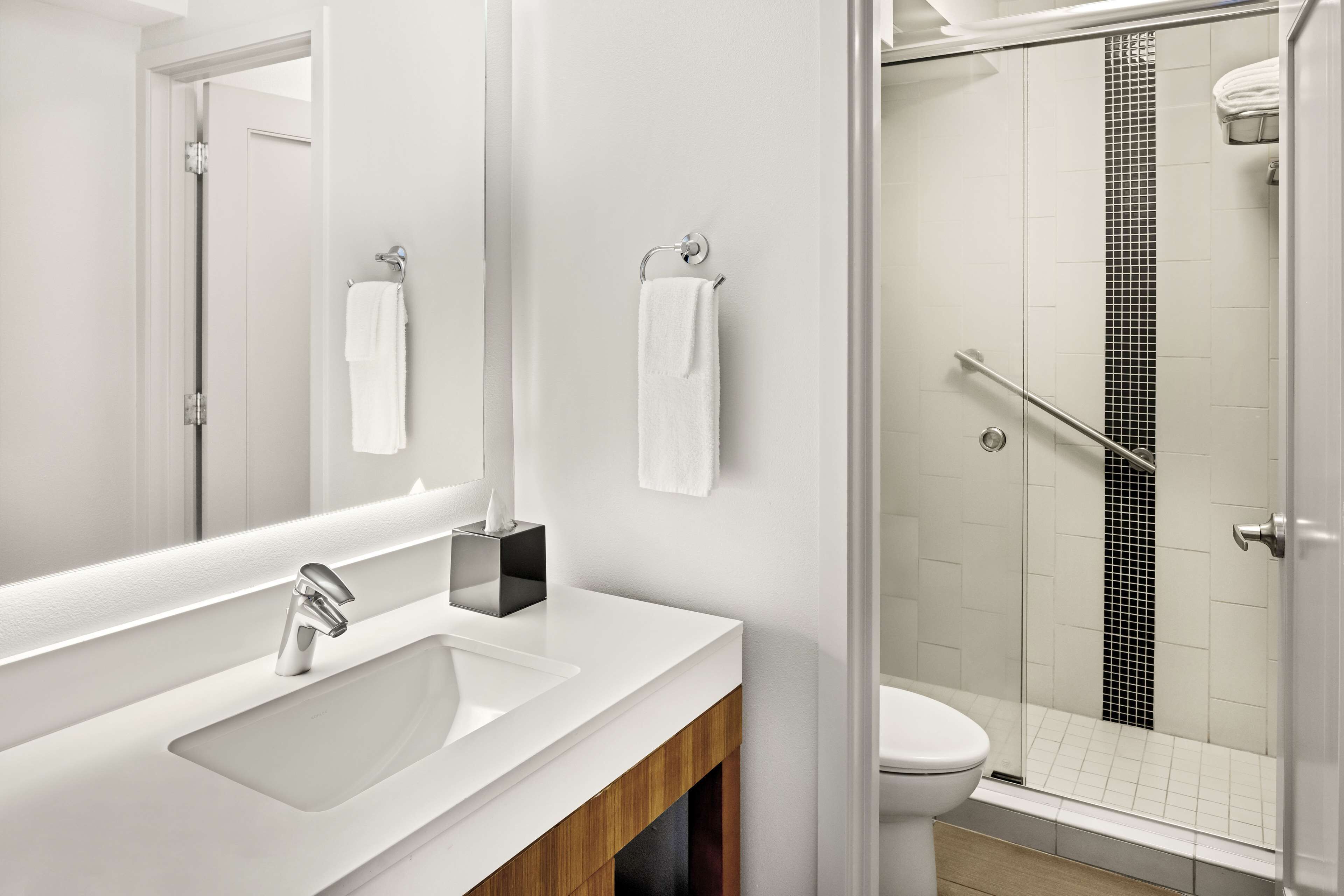 A modern bathroom with a white sink, mirror, and toilet.