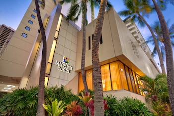 A modern lobby with seating areas, a large wall mural, and a reception desk. at Hyatt Place Waikiki Beach