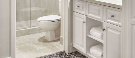 A modern bathroom with a glass-enclosed shower, a toilet, a vanity with a mirror, and a sink.