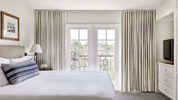 A hotel room with a bed, a television, a desk, and a window with curtains.