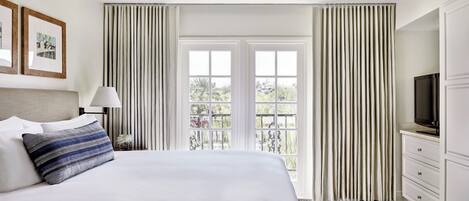 Une chambre d’hôtel avec un lit, une télévision, un bureau et une fenêtre avec des rideaux.