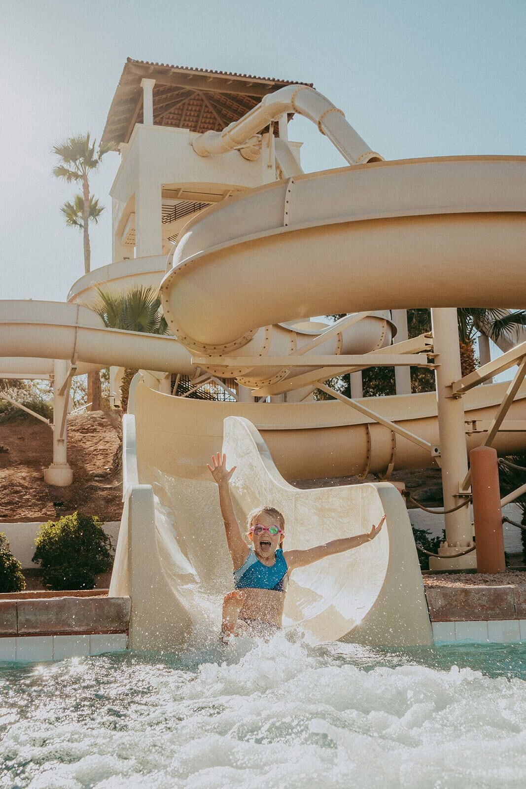 A water slide at a water park with a child sliding down.
