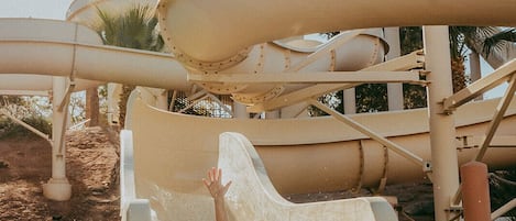 A water slide at a water park with a child sliding down.