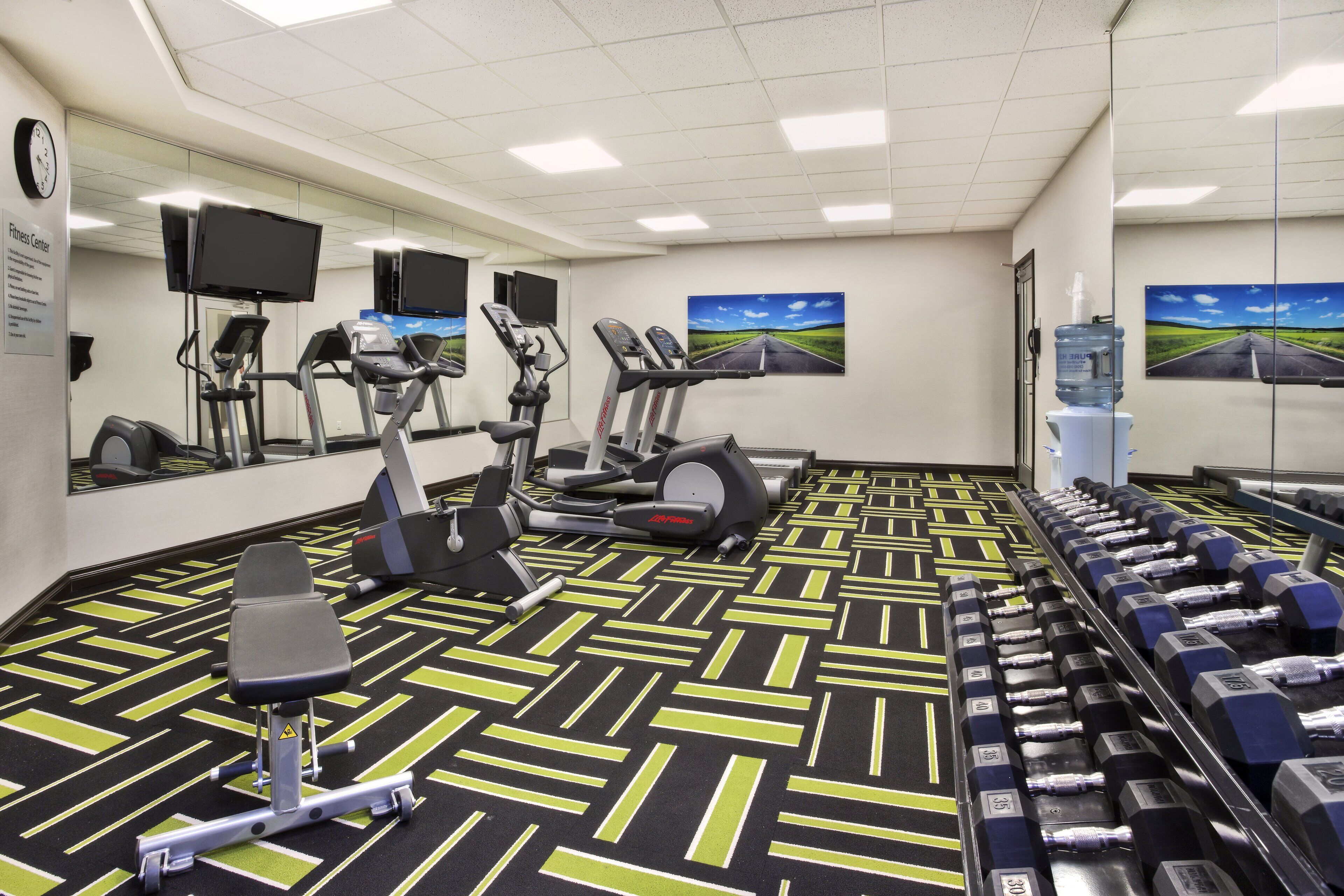 Ein Fitnessstudio mit Laufbändern, Ergometer und verschiedenen Gewichten.