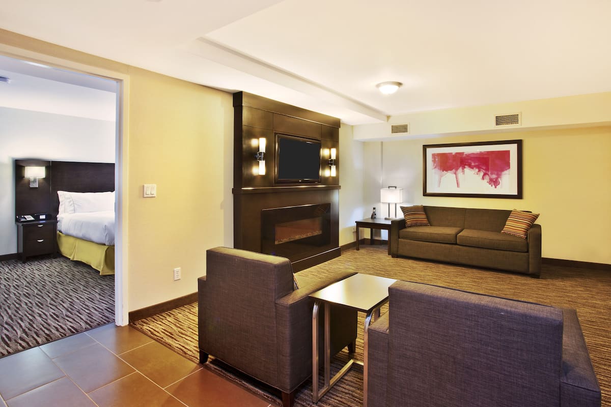 A hotel room with a bed, a sofa, a TV, and a small table.