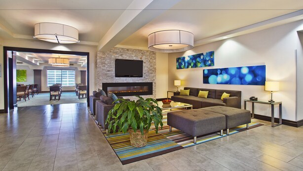 A spacious living area with a fireplace, comfortable seating, and a large flat-screen TV. - Holiday Inn Express Sault Ste Marie by IHG (Sault Ste. Marie)