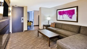 A hotel room with a sofa, a coffee table, a lamp, and a painting on the wall. - Holiday Inn Express Sault Ste Marie by IHG (Sault Ste. Marie)