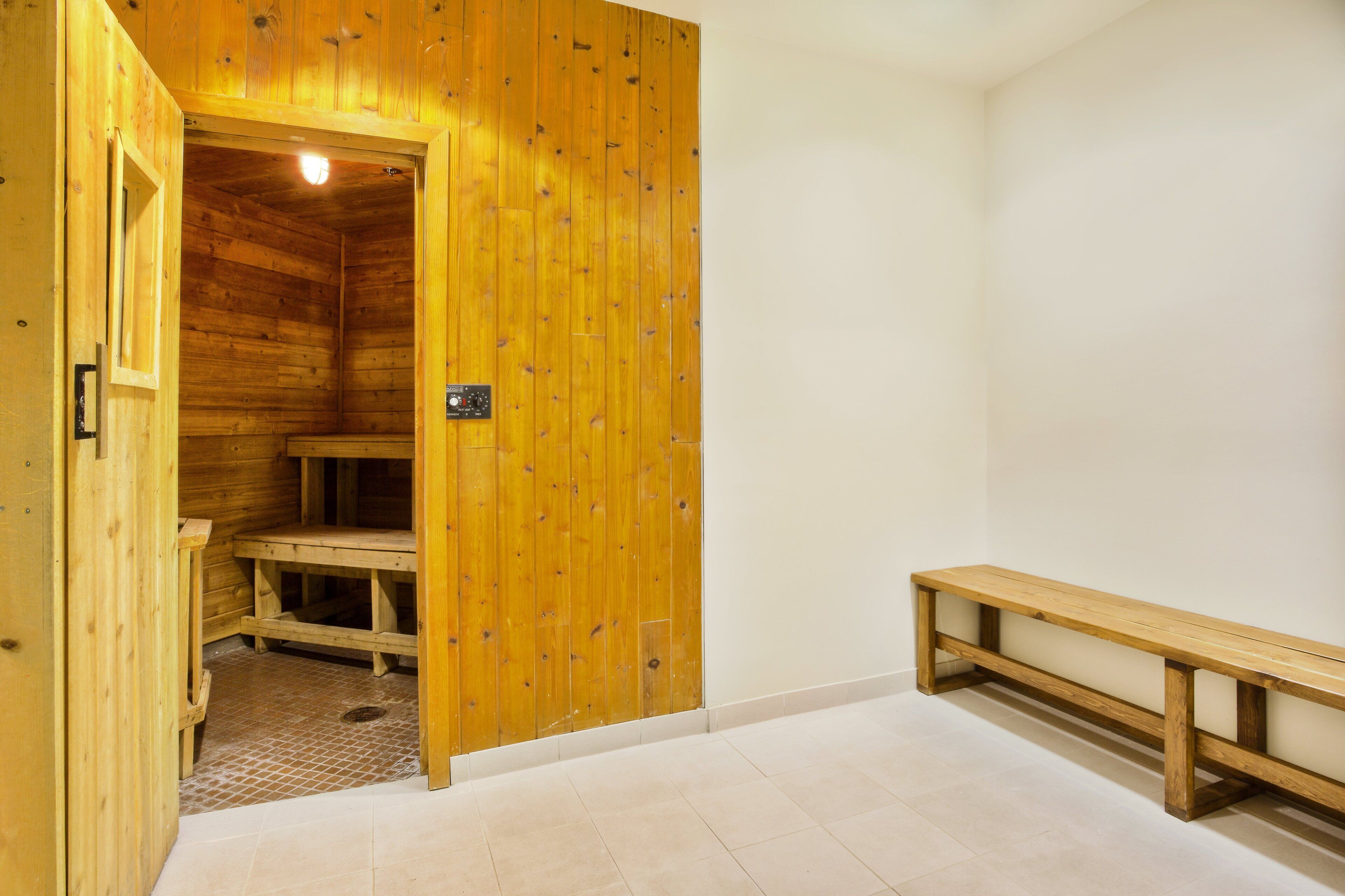 Un sauna en bois, équipé d’un banc et d’un panneau de commande.