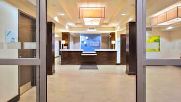 Área de recepção de hotel com balcão, placa da Holiday Inn Express e sinalização de porta corta-fogo.