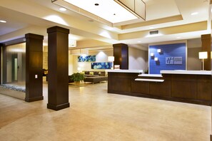 A hotel lobby with a reception desk, seating area, and a large window. - Holiday Inn Express Sault Ste Marie by IHG (Sault Ste. Marie)