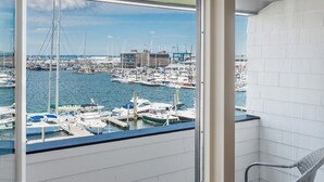 A balcony with a view of a marina, a wicker chair, a bottle of wine, and two glasses. - The Newport Harbor Hotel & Marina (Newport)