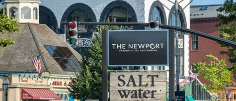 Une vue de rue avec une enseigne indiquant « The Newport Harbor Hotel and Marina » et « Salt Water Harborside Dining ».