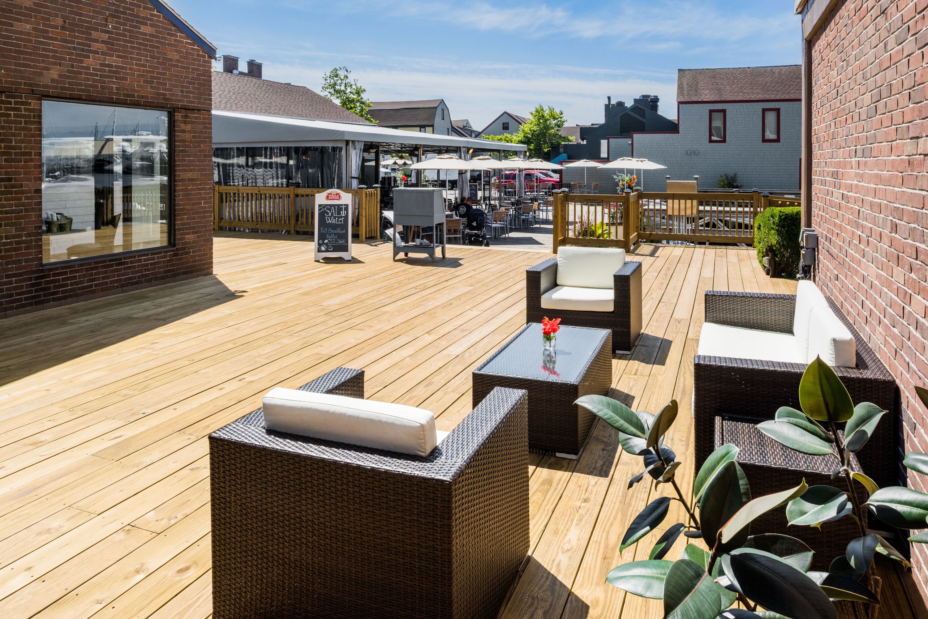 A wooden deck with wicker furniture, a table with a vase, and a signboard.