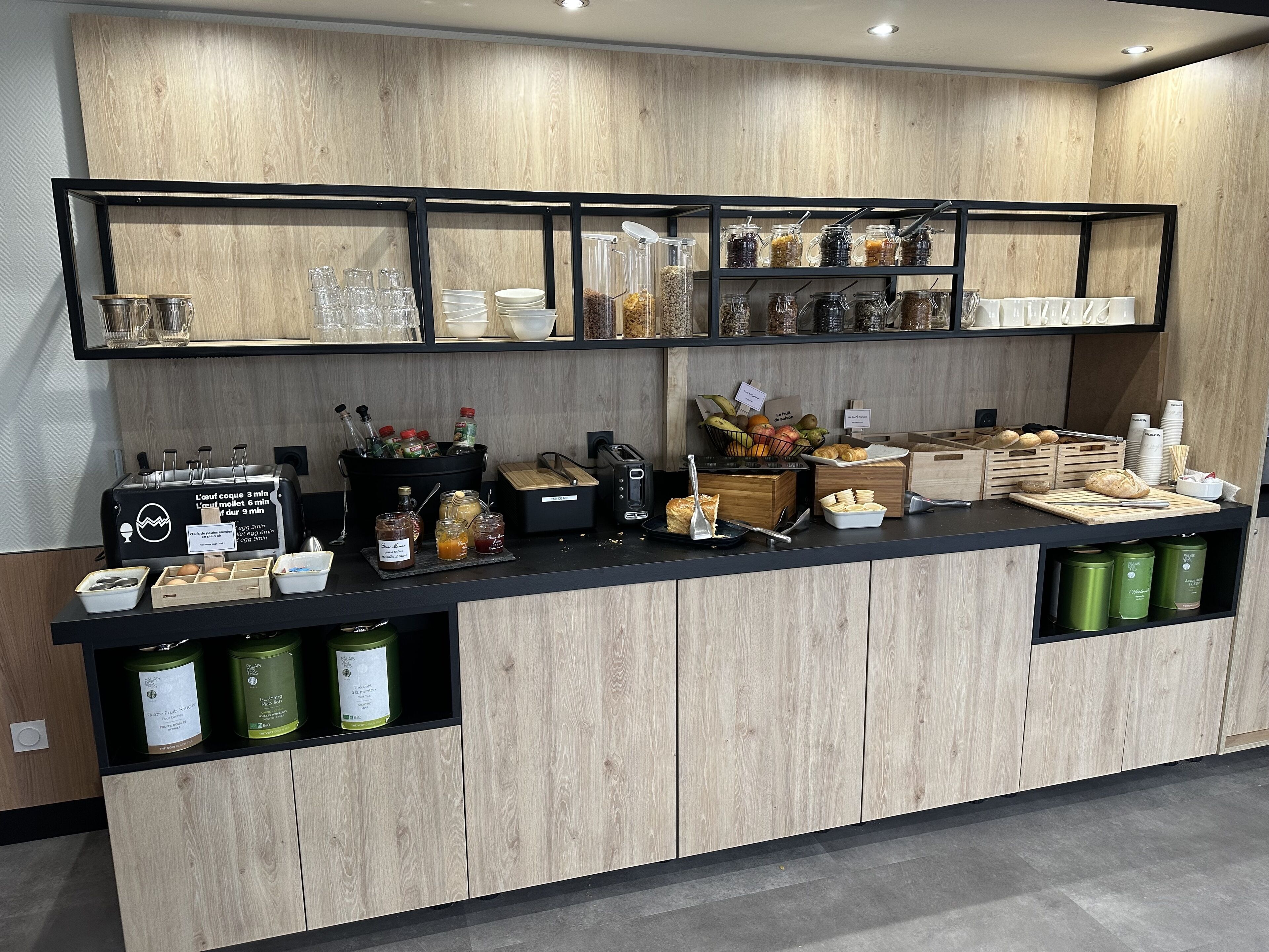 A breakfast bar with a variety of food items, including bread, pastries, and condiments.