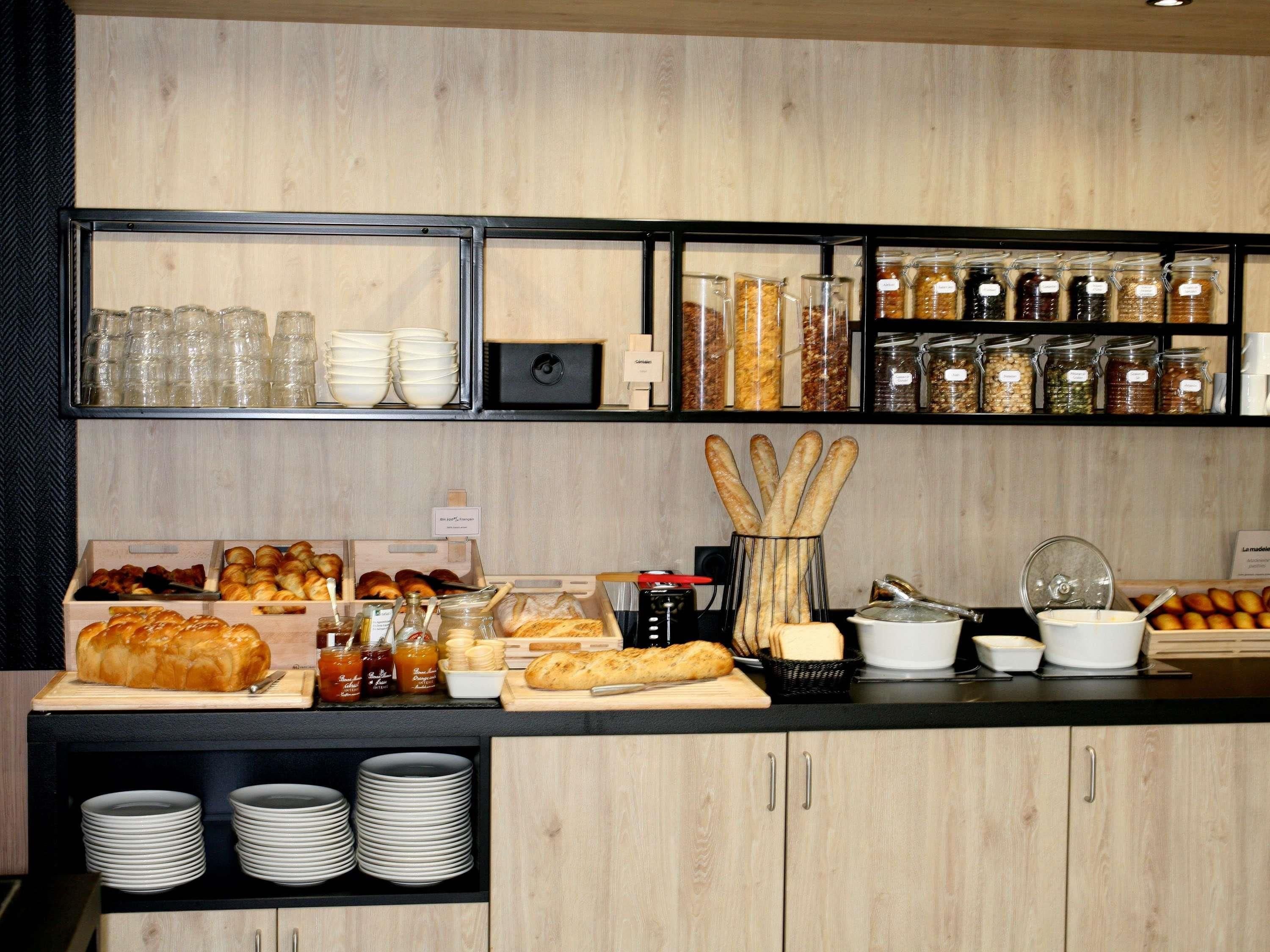 A breakfast buffet with various breads, pastries, and condiments.