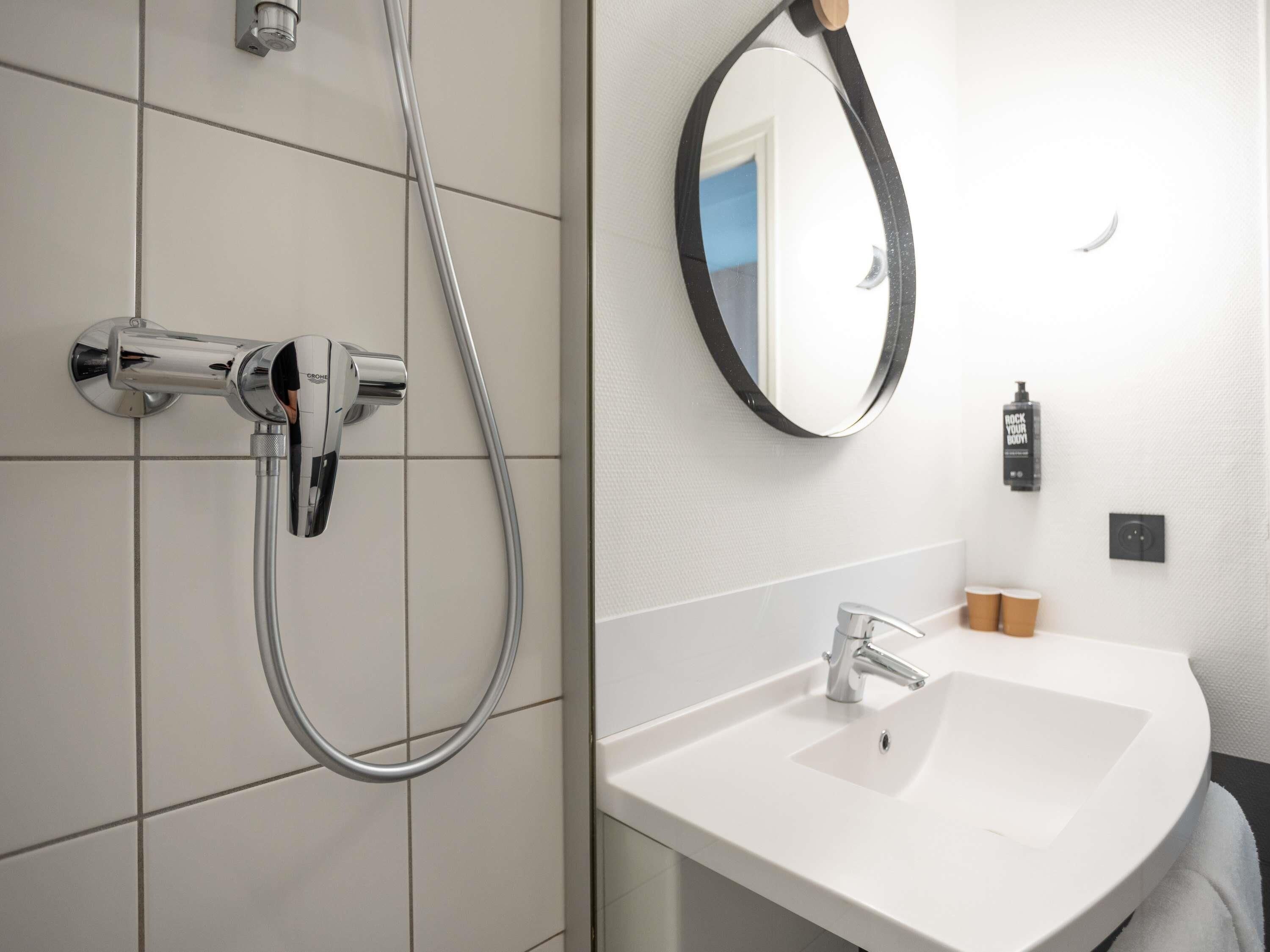 Une salle de bain moderne avec une douche, un lavabo et un miroir.