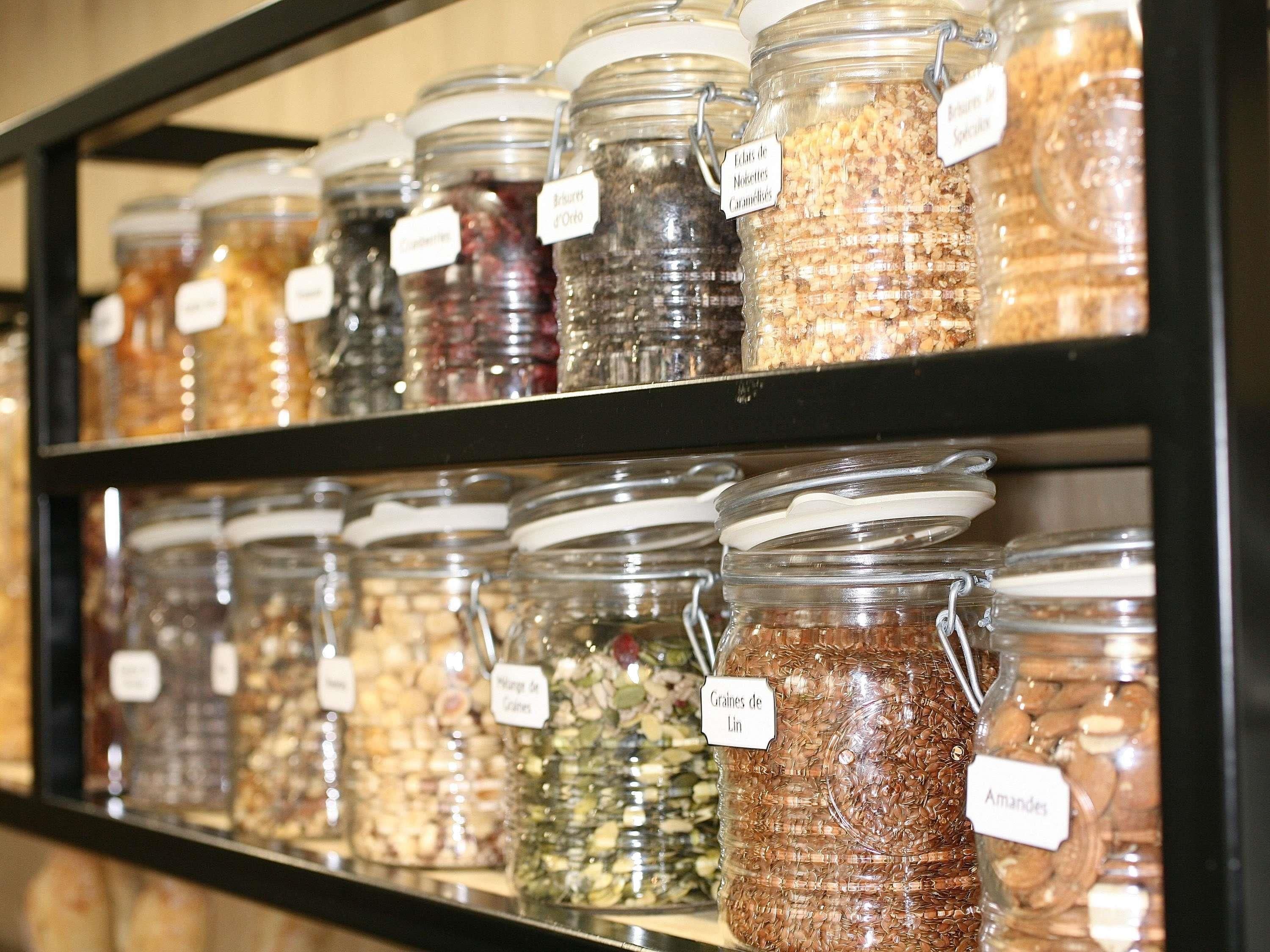 A shelf with glass jars labeled with various food items.