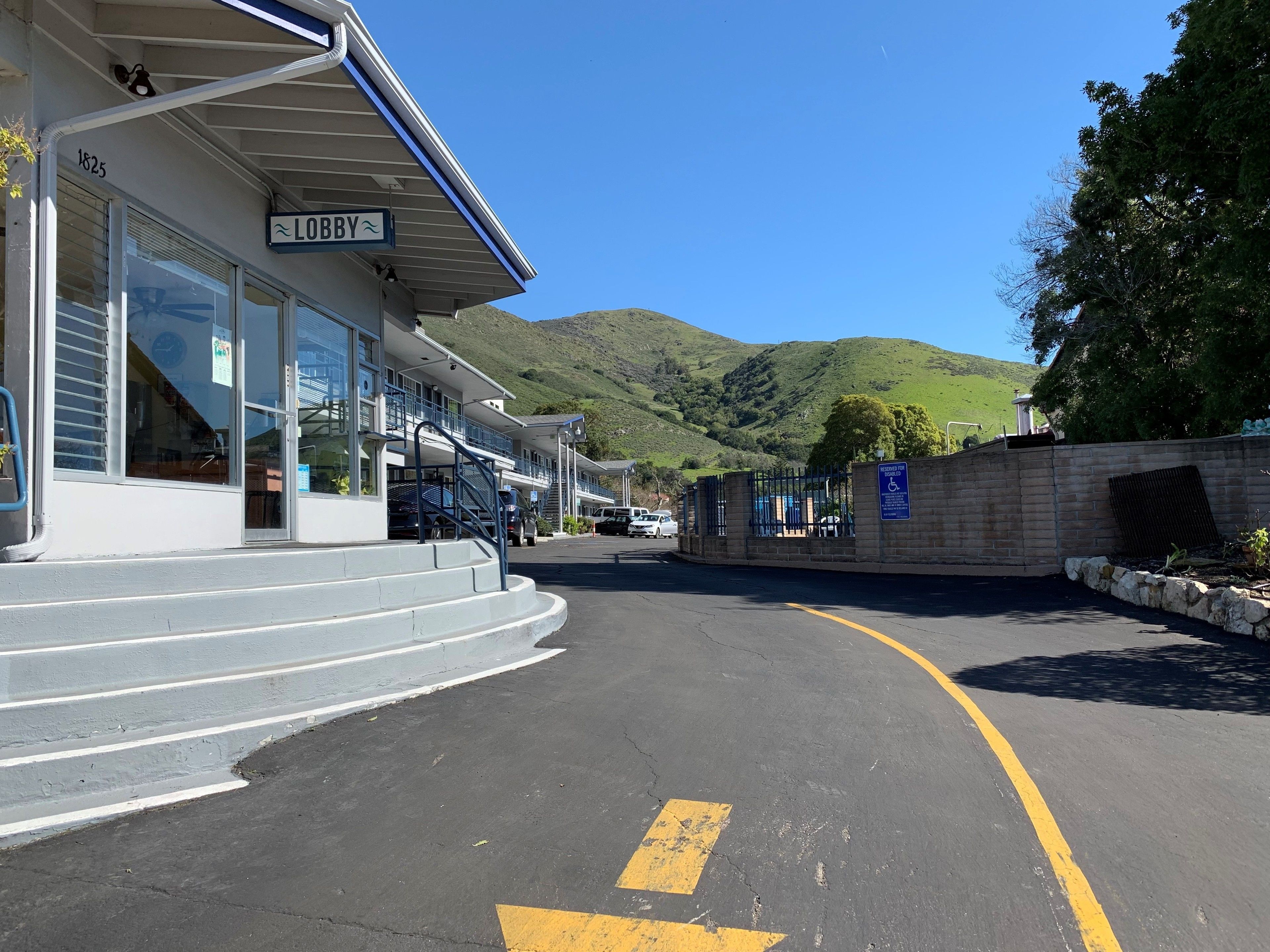A building with a sign reading "Lobby" and a parking area with a yellow directional arrow on the road.